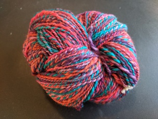 a skein of yarn in shadess of pink, orange, purple, and teal
